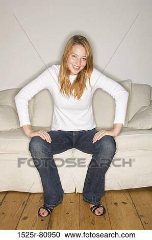 Portrait of a young woman sitting on a couch and smiling View Large Photo Image Stock Image - Portrait of a young woman sitting on a couch and smiling. Fotosearch