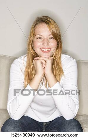 Portrait of a young woman sitting on a couch and smiling View Large Photo Image Stock Photo - Portrait of a young woman sitting on a couch and smiling. Fotosearch