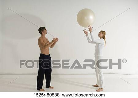 Side profile of a young couple playing with a fitness ball View Large Photo Image Stock Photo - Side profile of a young couple playing with a fitness ball. Fotosearch
