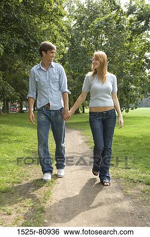 Young couple holding each other's hands and walking in a park View Large Photo Image Stock Photograph - Young couple holding each other's hands and walking in a park. Fotosearch
