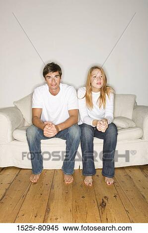 Young couple sitting on a couch View Large Photo Image Stock Photography - Young couple sitting on a couch. Fotosearch