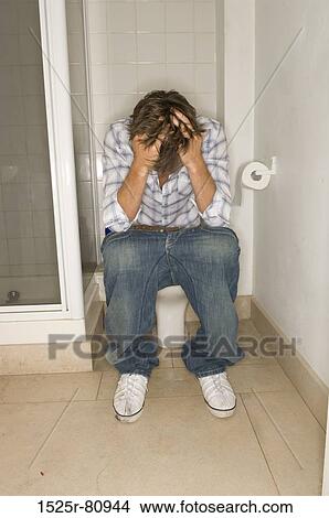 Young man sitting on a toilet View Large Photo Image Picture - Young man sitting on a toilet. Fotosearch