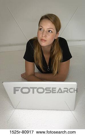 Young woman lying on the floor in front of a laptop View Large Photo Image Stock Photo - Young woman lying on the floor in front of a laptop. Fotosearch