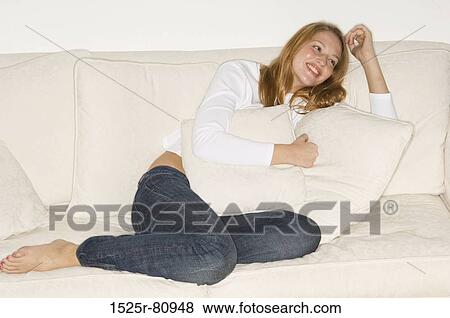 Young woman reclining on a couch and smiling View Large Photo Image Stock Photo - Young woman reclining on a couch and smiling. Fotosearch