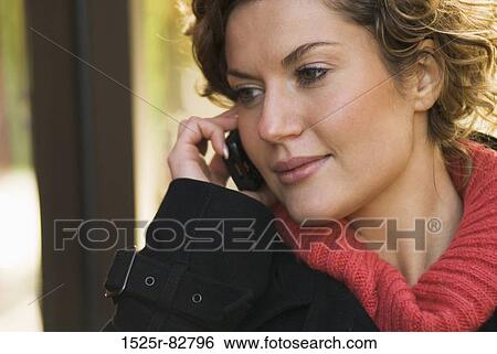 Close-up of a young woman talking on a mobile phone View Large Photo Image Stock Photograph - Close-up of a young woman talking on a mobile phone. Fotosearch