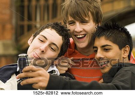 Stock Image - Close-up of three teenage boys taking a photograph of themselves with a mobile phone. Fotosearch