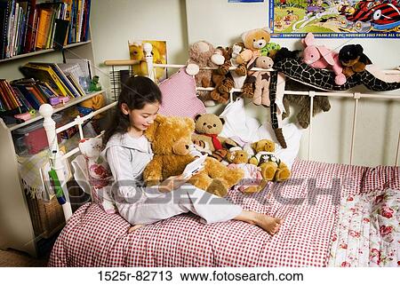 Stock Image - Girl holding a personal data assistant on the bed. Fotosearch