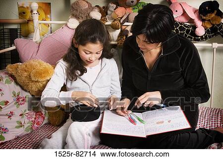 Picture - Girl with her mother studying on the bed. Fotosearch