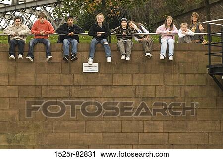Group of people sitting on a wall View Large Photo Image Stock Image - Group of people sitting on a wall. Fotosearch