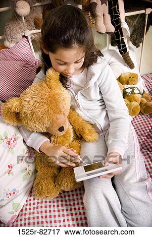 High angle view of a girl operating a personal data assistant View Large Photo Image Stock Photo - High angle view of a girl operating a personal data assistant. Fotosearch