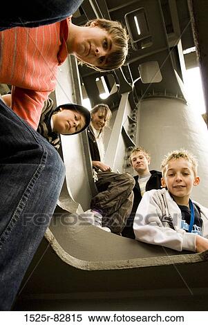 Stock Photography - Low angle view of four teenage boys and a teenage girl sitting on a bridge. Fotosearch