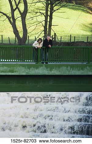 Mature couple leaning on the railing of a bridge View Large Photo Image Stock Image - Mature couple leaning on the railing of a bridge. Fotosearch