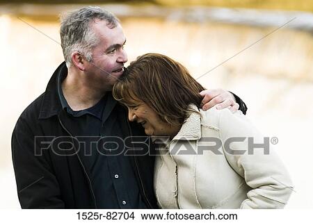 Mature man with his arm around a mature woman and smiling View Large Photo Image Picture - Mature man with his arm around a mature woman and smiling. Fotosearch