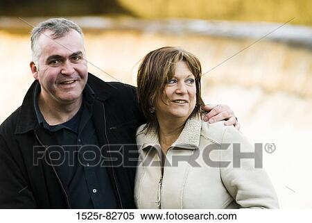Mature man with his arm around a mature woman and smiling View Large Photo Image Stock Photography - Mature man with his arm around a mature woman and smiling. Fotosearch