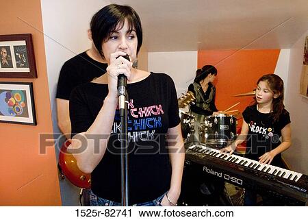 Mid adult woman singing with her daughter playing a synthesizer behind her View Large Photo Image Stock Image - Mid adult woman singing with her daughter playing a synthesizer behind her. Fotosearch