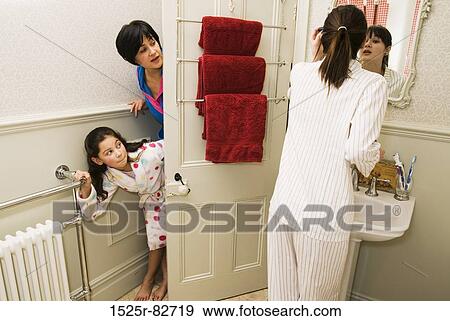 Mid adult woman with her daughter peeking at teenage girl standing in front of a mirror View Large Photo Image Stock Photo - Mid adult woman with her daughter peeking at teenage girl standing in front of a mirror. Fotosearch