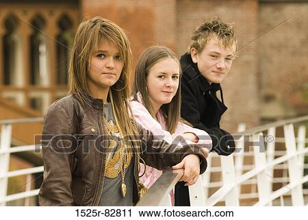 Teenage boy with two teenage girls standing against a railing View Large Photo Image Stock Image - Teenage boy with two teenage girls standing against a railing. Fotosearch