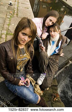 Stock Photo - Three teenage girls sitting near a canal. Fotosearch