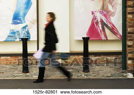 Stock Image - Woman walking by a store window. Fotosearch