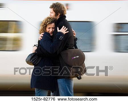 Stock Photograph - Young couple embracing each other at a railroad station platform. Fotosearch