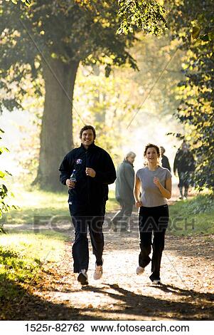 Young couple jogging on a dirt road in a park View Large Photo Image Stock Image - Young couple jogging on a dirt road in a park. Fotosearch