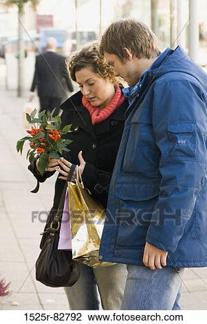 Young couple looking at a flower View Large Photo Image Stock Image - Young couple looking at a flower. Fotosearch