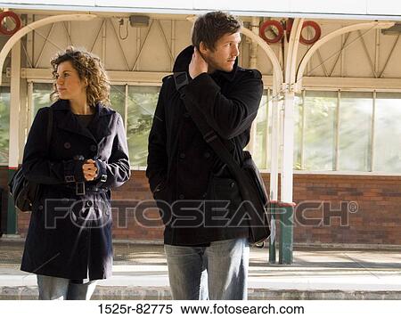 Stock Photography - Young couple standing at a railroad station platform. Fotosearch