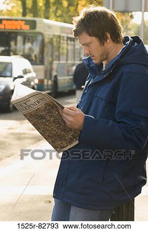 Young man reading a magazine on a sidewalk View Large Photo Image Stock Image - Young man reading a magazine on a sidewalk. Fotosearch