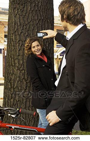Young man taking a picture of a young woman with a mobile phone View Large Photo Image Stock Photo - Young man taking a picture of a young woman with a mobile phone. Fotosearch