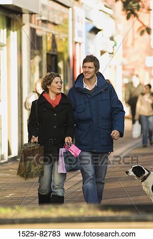 Young man walking with a young woman carrying shopping bags View Large Photo Image Stock Image - Young man walking with a young woman carrying shopping bags. Fotosearch
