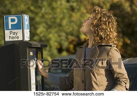 Picture - Young woman standing near a parking meter. Fotosearch
