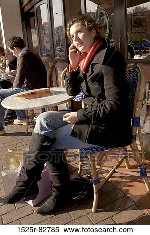Young woman talking on a mobile phone in a sidewalk cafe View Large Photo Image Stock Photography - Young woman talking on a mobile phone in a sidewalk cafe. Fotosearch
