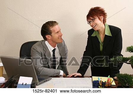 Businessman sitting in an office with his secretary standing beside him View Large Photo Image Stock Image - Businessman sitting in an office with his secretary standing beside him. Fotosearch
