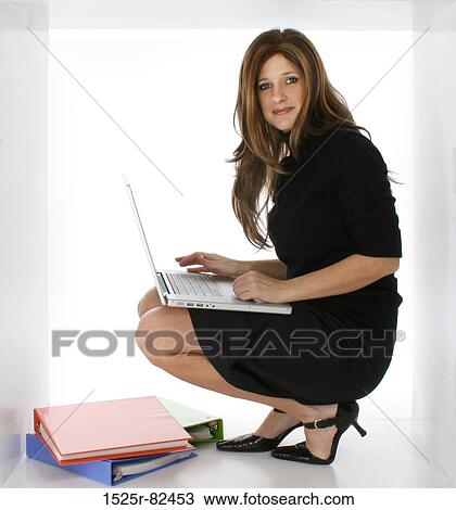 Businesswoman crouching with a laptop on her lap under a low ceiling View Large Photo Image Stock Image - Businesswoman crouching with a laptop on her lap under a low ceiling. Fotosearch