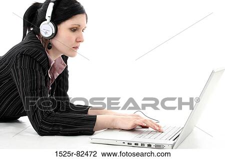Stock Image - Businesswoman listening to music and working on a laptop. Fotosearch