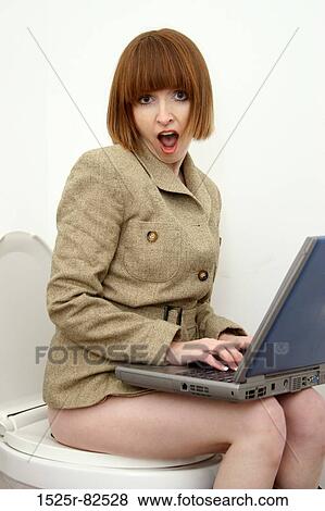 Stock Photo - Businesswoman sitting on a toilet and working on a laptop. Fotosearch