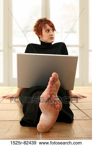Stock Photo - Businesswoman sitting on the floor with a laptop on her lap. Fotosearch