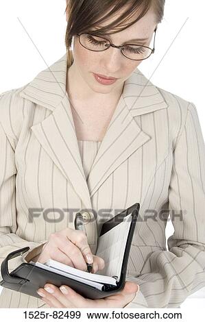 Stock Photo - Close-up of a businesswoman writing in a personal organizer. Fotosearch