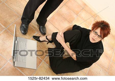 High angle view of a businesswoman sitting on the floor near a laptop and a businessman standing beside her View Large Photo Image Picture - High angle view of a businesswoman sitting on the floor near a laptop and a businessman standing beside her. Fotosearch