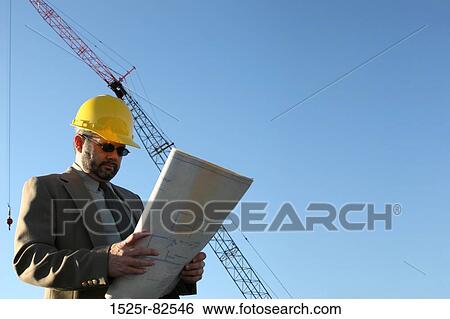 Low angle view of an architect reading a blueprint at a construction site View Large Photo Image Stock Photograph - Low angle view of an architect reading a blueprint at a construction site. Fotosearch