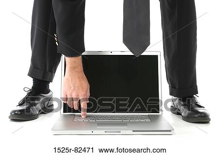 Stock Image - Low section view of a businessman working on a laptop between his leg. Fotosearch