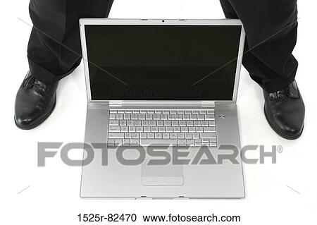 Stock Image - Low section view of a man standing with a laptop between his legs. Fotosearch