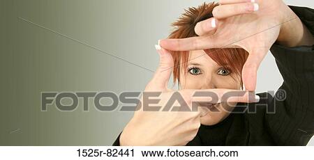 Stock Image - Portrait of a mid adult woman making a finger frame in front of her eyes. Fotosearch