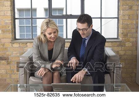 Businessman and a businesswoman looking at a laptop View Large Photo Image Stock Photography - Businessman and a businesswoman looking at a laptop. Fotosearch