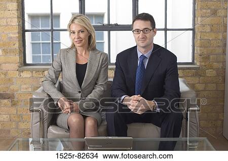 Businessman and a businesswoman sitting on a couch View Large Photo Image Picture - Businessman and a businesswoman sitting on a couch. Fotosearch