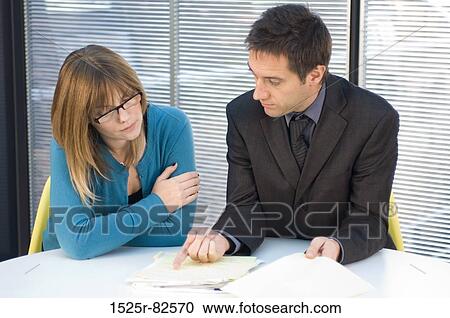 Stock Image - Businessman and a businesswoman sitting at a desk. Fotosearch