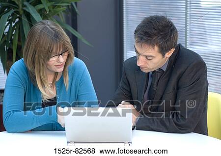Businessman and a businesswoman sitting in front of a laptop View Large Photo Image Stock Photo - Businessman and a businesswoman sitting in front of a laptop. Fotosearch