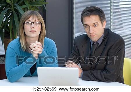 Businessman and a businesswoman sitting in front of a laptop View Large Photo Image Stock Photo - Businessman and a businesswoman sitting in front of a laptop. Fotosearch