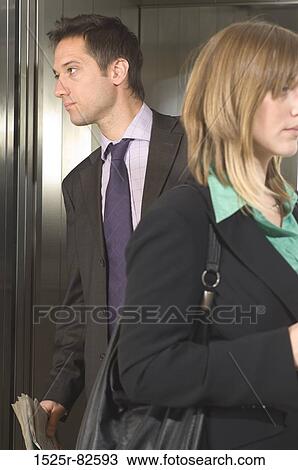 Businessman and a businesswoman standing in an elevator View Large Photo Image Stock Image - Businessman and a businesswoman standing in an elevator. Fotosearch