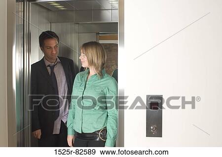 Businessman and a businesswoman standing in an elevator View Large Photo Image Stock Photo - Businessman and a businesswoman standing in an elevator. Fotosearch